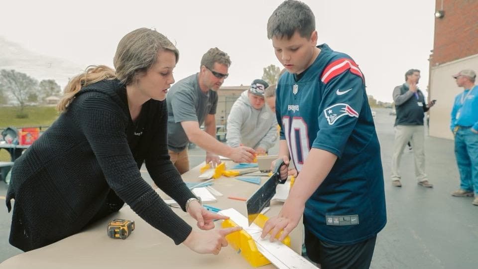 A TradesNKY mentor guides a Campbell County Middle School student through a hand-saw cut during a hands-on workshop