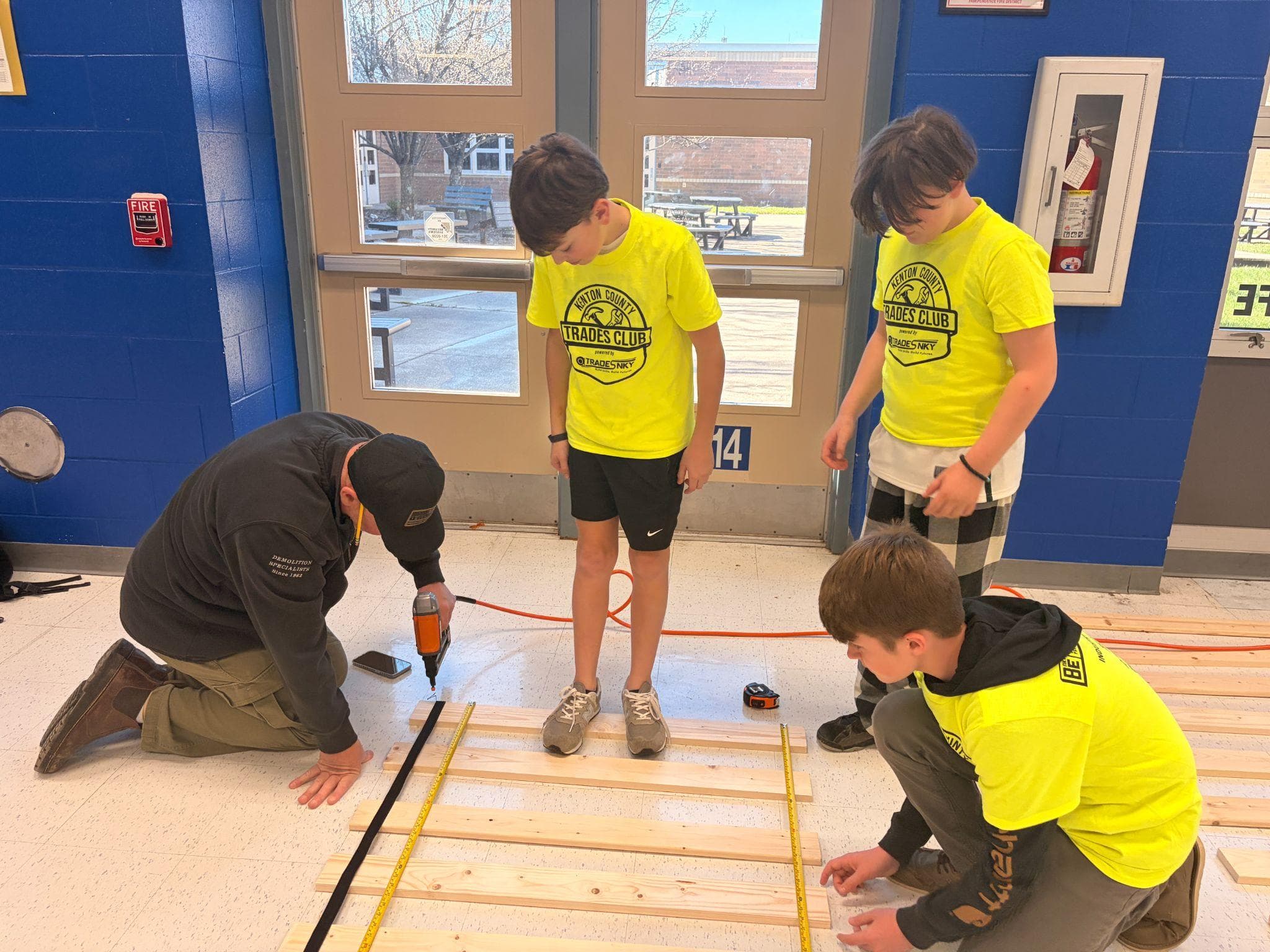 Kenton County Trades Club students measure and assemble bed slats alongside an industry mentor