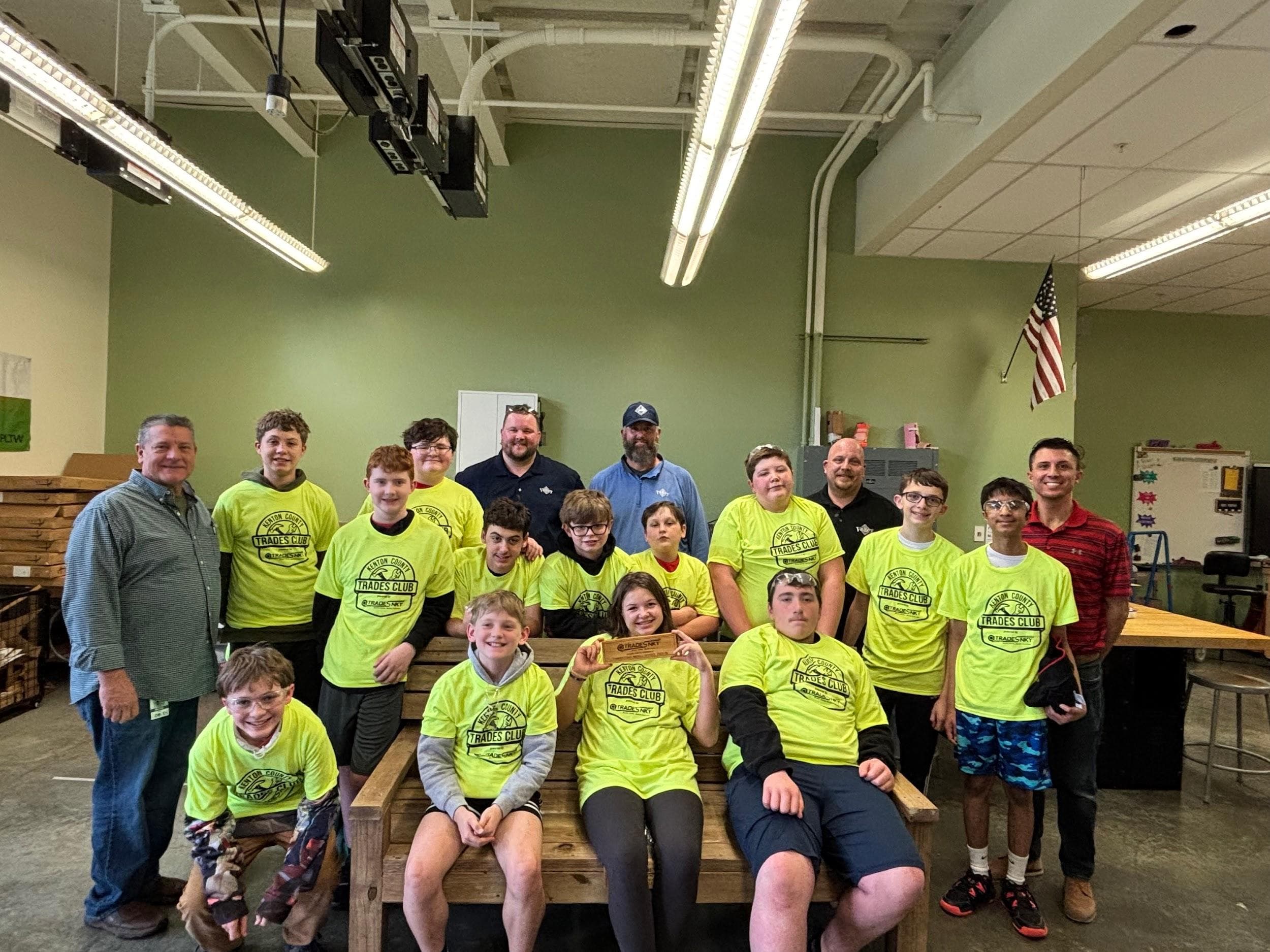 Kenton County Trades Club students gather around an outdoor bench they built for donation to a local community organization
